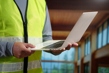 A professional construction engineer or site supervisor stands confidently in a modern wooden...