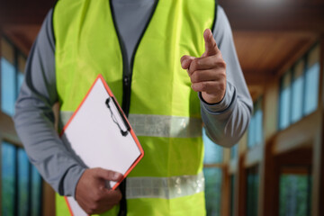 A professional construction engineer or site supervisor stands confidently in a modern wooden...