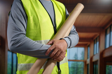 A professional construction engineer or site supervisor stands confidently in a modern wooden...