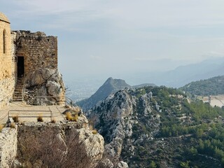 St. Hilarion Castle rising high in the Kyrenia Mountains with the distant coastal city of Kyrenia visible below, featuring dramatic cliffs, medieval stone walls, and sweeping views of northern Cyprus