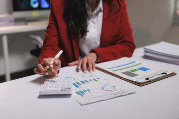 Businesswoman calculating finances using calculator with financial charts