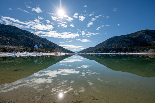 Sunny winter morning cloudscape over Grass Valley Reservoir in Harvey Gap State Park, Colorado reflected in reservoir's calm water.