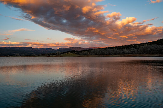 Intensely colorful sunset cloudscape over Grass Valley Reservoir in Harvey Gap State Park, Colorado reflected in reservoir's calm water.