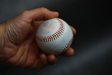 Close-Up of Hand Holding Baseball with Focus on Red Stitching and Textured Surface