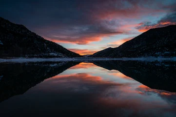 Poster Reflectie Intensely colorful sunset cloudscape over Grass Valley Reservoir in Harvey Gap State Park, Colorado reflected in reservoir's calm water.  © Francisco