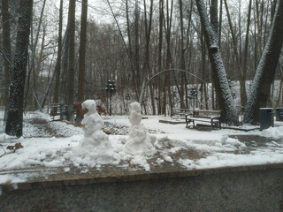 Miniature Snowmen Figures on Stone Ledge in Snowy Winter Park Forest Landscape_1