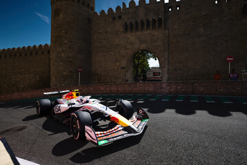Obraz premium BAKU, AZERBAIJAN - SEPTEMBER 20, 2025: A Visa Cash App RB Formula 1 car accelerates past the historic fortress walls of the Old City (Icherisheher) during the Azerbaijan Grand Prix