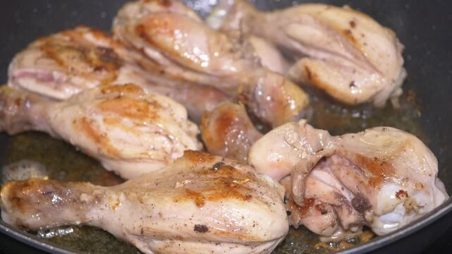 Cooking chicken drumsticks in a frying pan on the stove
