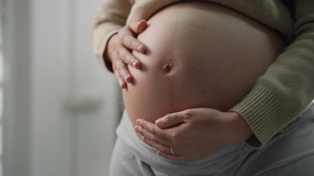 Happy pregnant woman or mother touching baby in belly with love at home. Health care, Prenatal preparation, Maternity, Pregnancy, and motherhood concept