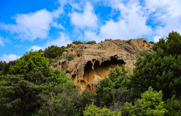 A stunning view of ancient granite rock formations called tafoni featuring natural hollow caves carved by wind in wild Sardinia