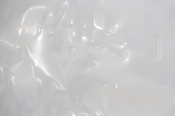 plastic transparent cellophane bag on white background. The texture looks blank and shiny. The plastic surface is wrinkly and tattered making abstract pattern