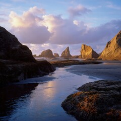 Fototapeta premium Dramatic coastal rock formations at sunset with reflective water