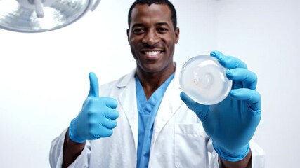 Medical Professional Showing Breast Implant: A smiling medical professional, in sterile gloves and a lab coat, proudly displays a breast implant.