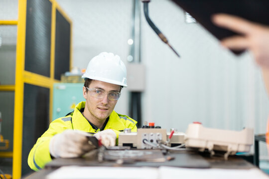 Technician in safety helmet performing electrical equipment testing in controlled industrial environment, focusing on system efficiency and reliability. - Powered by Adobe