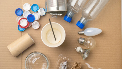 A messy table with various items such as a can, a bottle, a cup, and a light bulb. The table is covered in trash, including a pile of plastic bottles and a cup