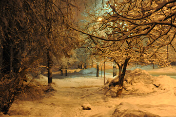 Snowy winter night path illuminated by warm streetlights, creating a magical atmosphere