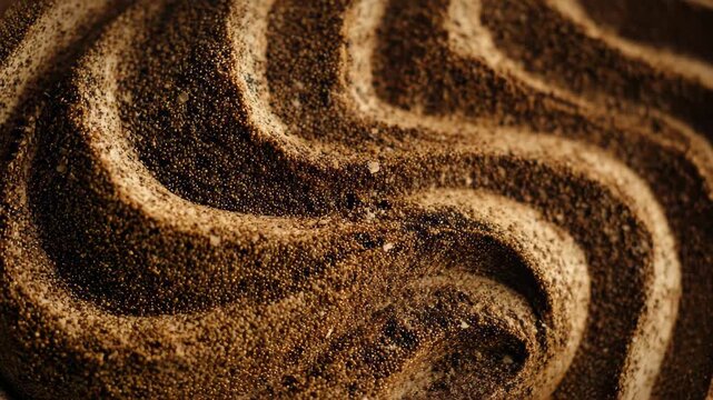 Coffee grounds arranged in wavy patterns on a surface showing the texture and details of the dark material at a kitchen countertop during daylight hours