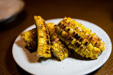 A cob of yaki tomorokoshi grilled corn brushed with soy butter, placed on a ceramic dish