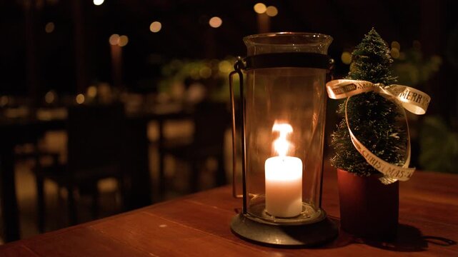 Burning Pillar Candle in Glass Hurricane Lantern on Restaurant Table