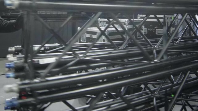 Workers carry metal frame carcass for stage maintaining in concert hall closeup. Employees assemble concert equipment at festival location