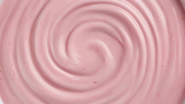 Pink creamy swirl texture background. close-up overhead shot of berry yogurt frosting or ice cream surface creating a smooth appetizing spiral pattern.