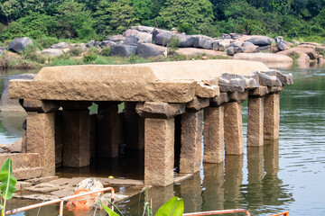 Old stone structure near water with trees and rocks in the background during daylight hours