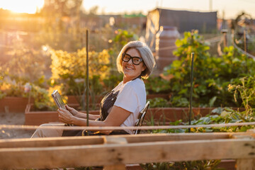 Mature woman enjoying hobby gardening with digital tablet