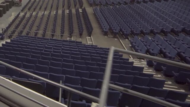 Numerous rows of empty seats in large arena with aisles and staircases providing access. Vast capacity of venue ready for audience to fill