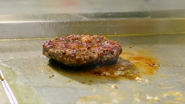 Chef hands insert meat thermometer probe into cutlet frying on grill closeup. Cook master controls burger patty preparation in restaurant kitchen