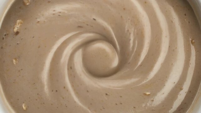 Macro shot of creamy beige textured swirl dessert or thick sauce forming a beautiful vortex pattern.