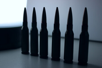 A Straight Row of Bullets for a Carbine Are Illuminated by the Light of a Camping Lamp on the Background