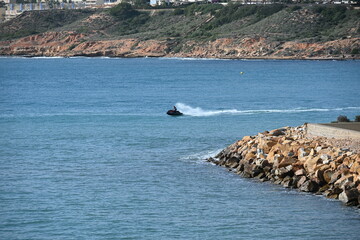 Man Riding a Jet Ski Near a High Rocky Coast on a Sunny Day
