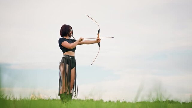 woman archer leather warrior in field aiming bow with focused stance against soft sky, quiver at hip, long skirt motion, single figure evokes solitude and strength, practicing draw and release,