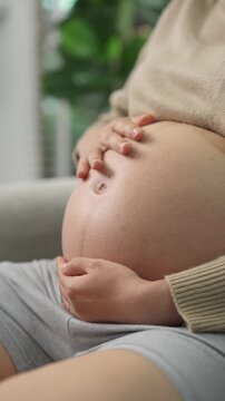 Happy pregnant woman or mother touching baby in belly with love at home. Health care, Prenatal preparation, Maternity, Pregnancy, and motherhood concept