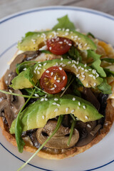 Avocado toast waffle with mushrooms, tomatoes, and arugula