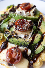 Avocado toast with cheese, tomatoes, balsamic glaze, and seeds