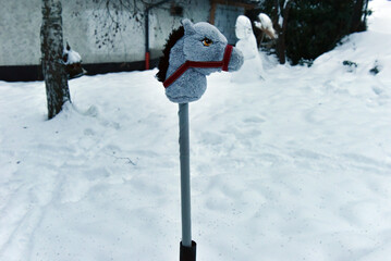 Grey plush hobby horse toy in the snow