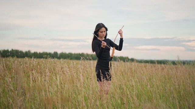 Woman practicing sword in tall grass, drawing slender blade from sheath and rehearsing fluid strikes, focused footwork and disciplined gestures, ritual training at twilight across rural horizon,