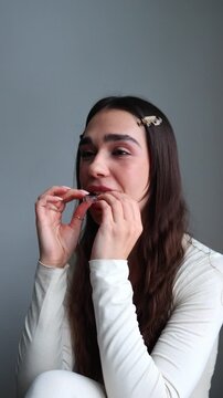 A young woman smiles and shows an "OK" hand gesture while putting transparent dental aligners on her teeth. This shot highlights patient satisfaction with orthodontic care.
