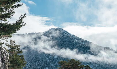 Snow-covered mountain peak surrounded by mist and clouds in winter