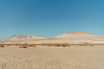 Desert mountains and moon under clear sky in Fuerteventura