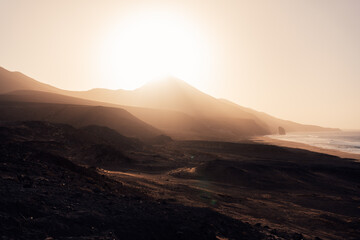 Sunset light over volcanic mountains and coastline at Cofete beach