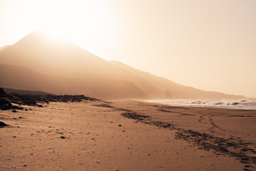 Footprints on empty Cofete beach at sunset