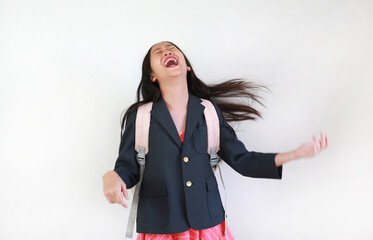 A cheerful young girl in school uniform laughing heartily and shaking her hair with joy after school.