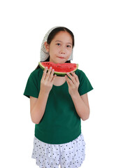 Portrait of Asian girl happily biting into slice fresh watermelon. She wearing dark green t-shirt, white polka dot shorts, and a polka dot bandana, capturing a refreshing summer moment.