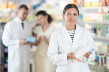 Young female pharmacist in medical uniform posing while working in pharmacy