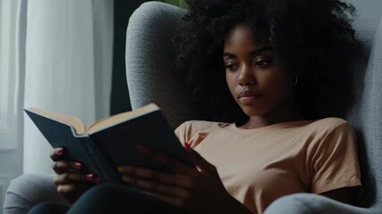 A young woman engrossed in a book, relaxing on a sofa.