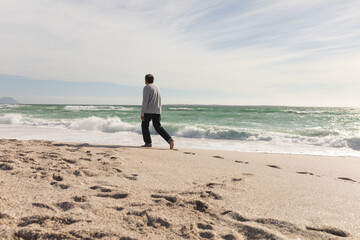Full length of retired senior man walking on shore at beach during sunny day