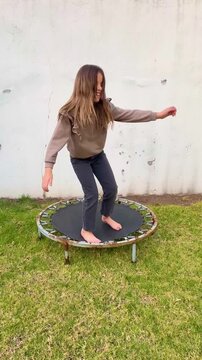 Little Girl Having Fun Playing on Mini Trampoline in Home Garden