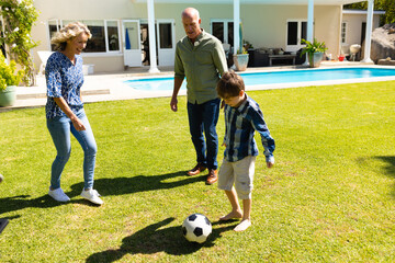Caucasian grandparents and grandson playing football together in garden